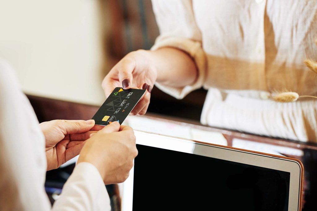 Credit card in hands female receptionist returning it to client after accepting payment